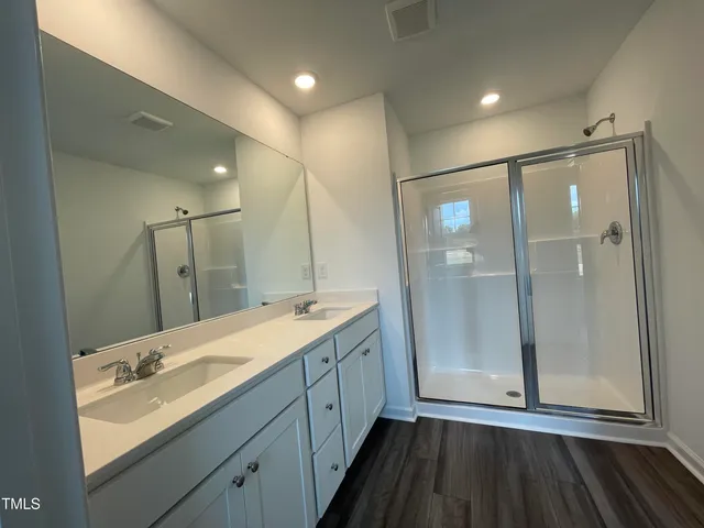 a bathroom with a double vanity sink mirror and shower