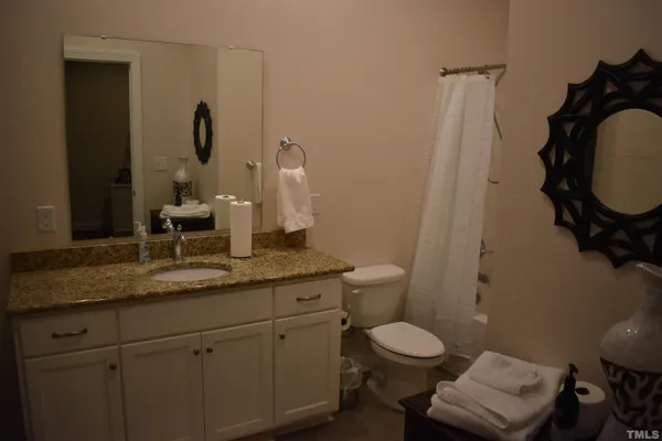 a bathroom with a granite countertop toilet sink and mirror