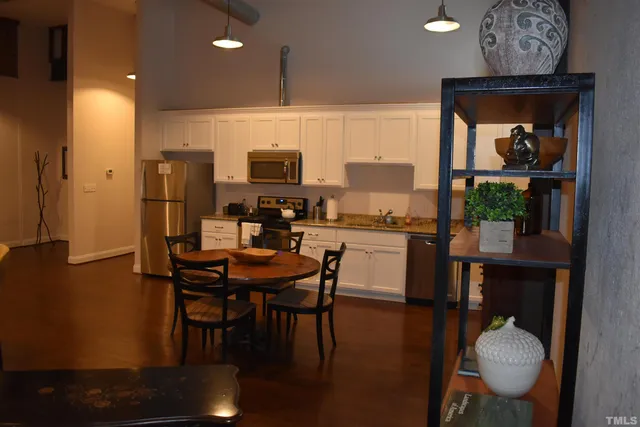 a kitchen with stainless steel appliances a dining table chairs refrigerator and sink