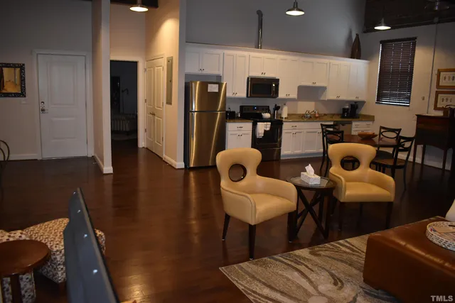 a kitchen with stainless steel appliances refrigerator dining table and chairs