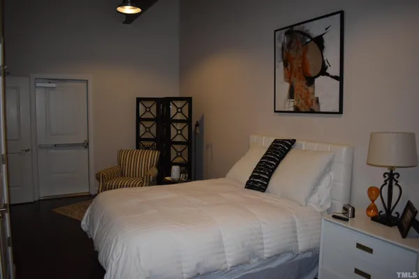 a bedroom with a bed and a lamp on dresser