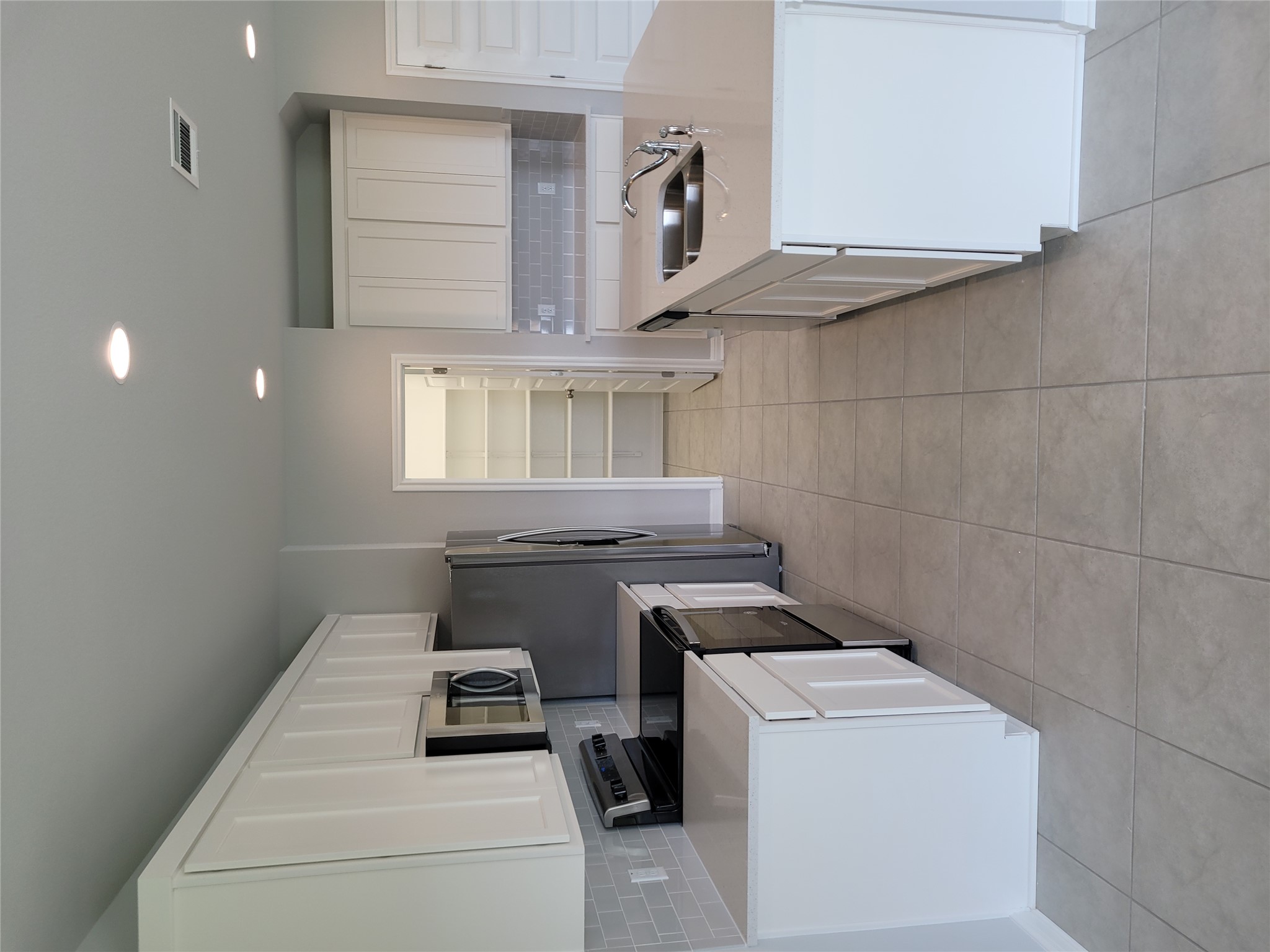 131 Wild Wind Cove Jarrell, TX 76537 - Photo 10 of 26 Modern kitchen featuring white cabinetry, light countertops, stainless steel appliances, a subway tile backsplash, and recessed lighting