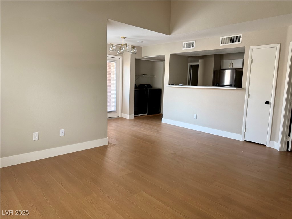 1150 North Buffalo Drive, Unit 2025 Las Vegas, NV 89128 - Photo 15 of 20 Unfurnished living room with a chandelier and wood finished floors