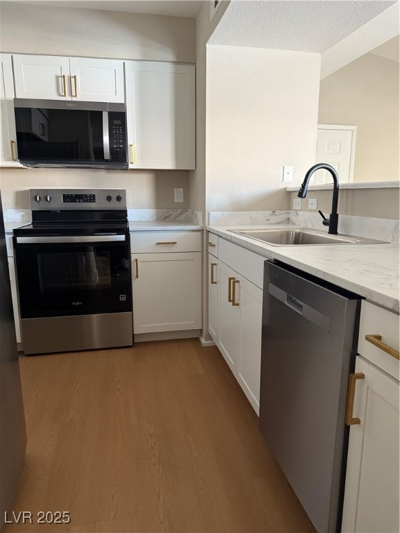 1150 North Buffalo Drive, Unit 2025 Las Vegas, NV 89128 - Photo 16 of 20 Kitchen with dishwasher, stove, light wood-style floors, white cabinetry, and light stone counters
