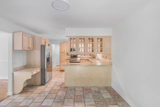 a view of a kitchen with kitchen island granite countertop a refrigerator and a sink
