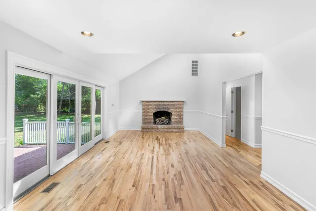 a view of empty room with wooden floor and fireplace