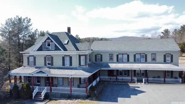 a view of a big house with a fountain plants and large trees