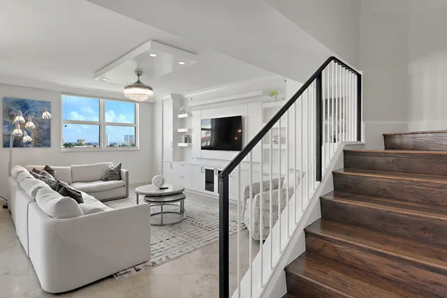 a living room with couches and stairs with wooden floor
