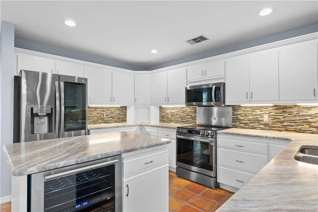 a kitchen with stainless steel appliances granite countertop a stove top oven a sink and white cabinets