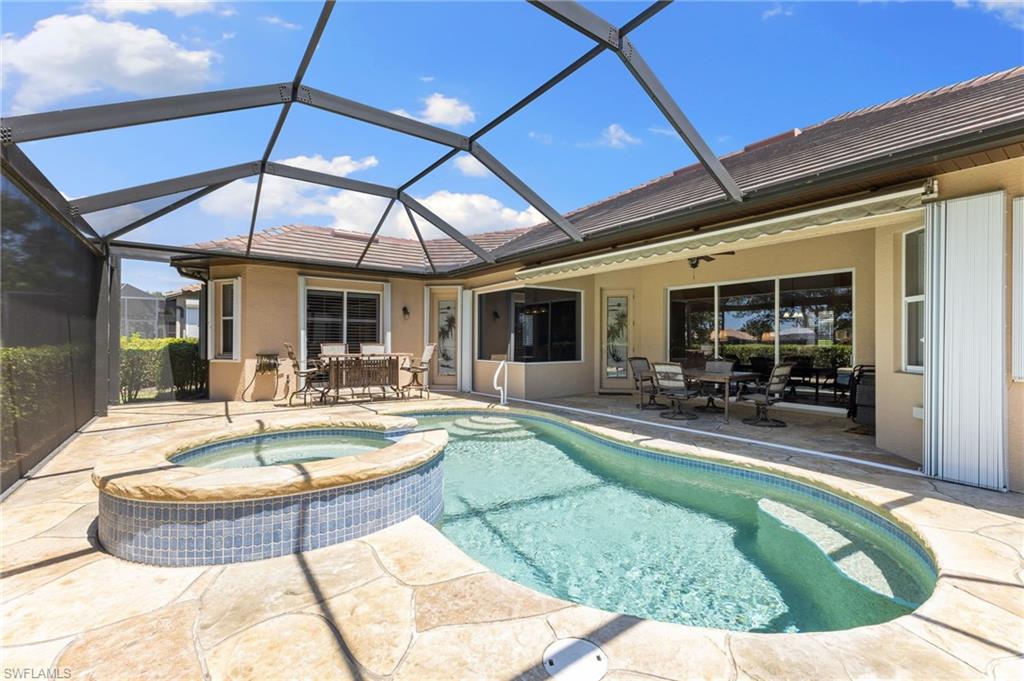 8886 Lely Island Circle Naples, FL 34113 - Photo 12 of 44 a view of a patio with dining table and chairs under an umbrella