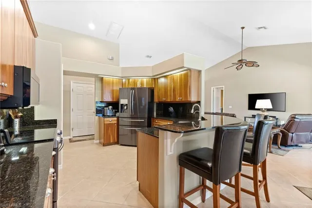 a kitchen with stainless steel appliances kitchen island granite countertop a table chairs microwave and sink