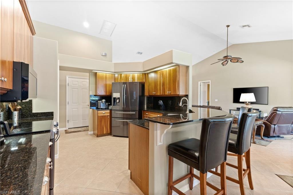 8886 Lely Island Circle Naples, FL 34113 - Photo 24 of 44 a kitchen with stainless steel appliances kitchen island granite countertop a table chairs microwave and sink
