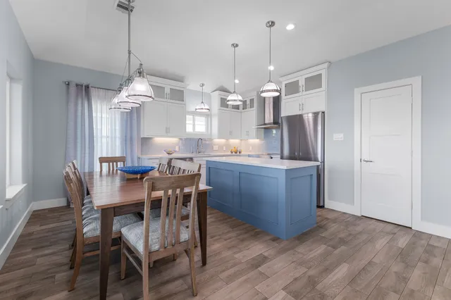 a kitchen with stainless steel appliances granite countertop a table chairs and a refrigerator