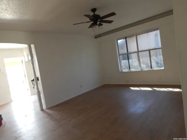 an empty room with wooden floor and windows with curtains