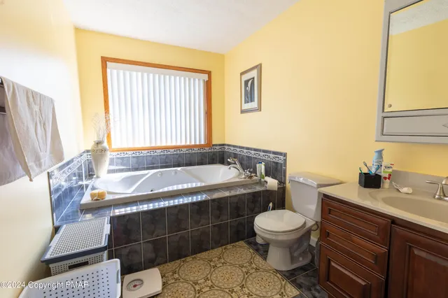 a bathroom with a granite countertop bathtub sink vanity mirror and toilet