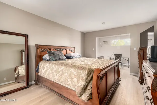 a bedroom with a bed and a flat tv screen on dresser