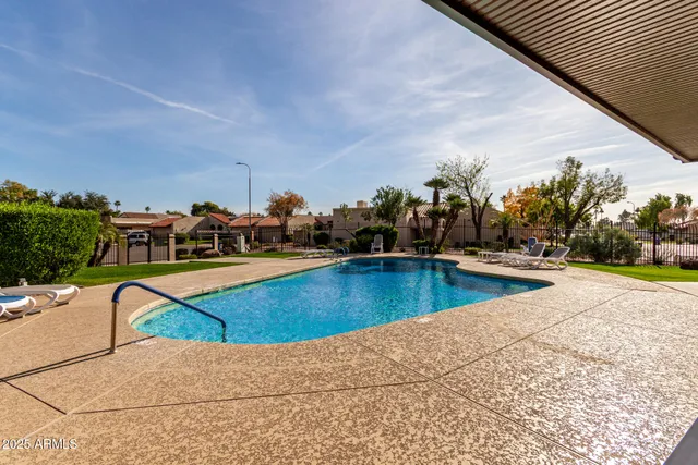 a view of swimming pool with outdoor seating and trees in the background