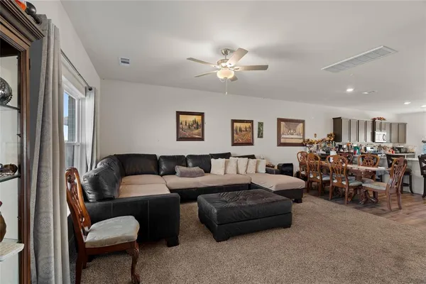 a living room with furniture ceiling fan and a flat screen tv