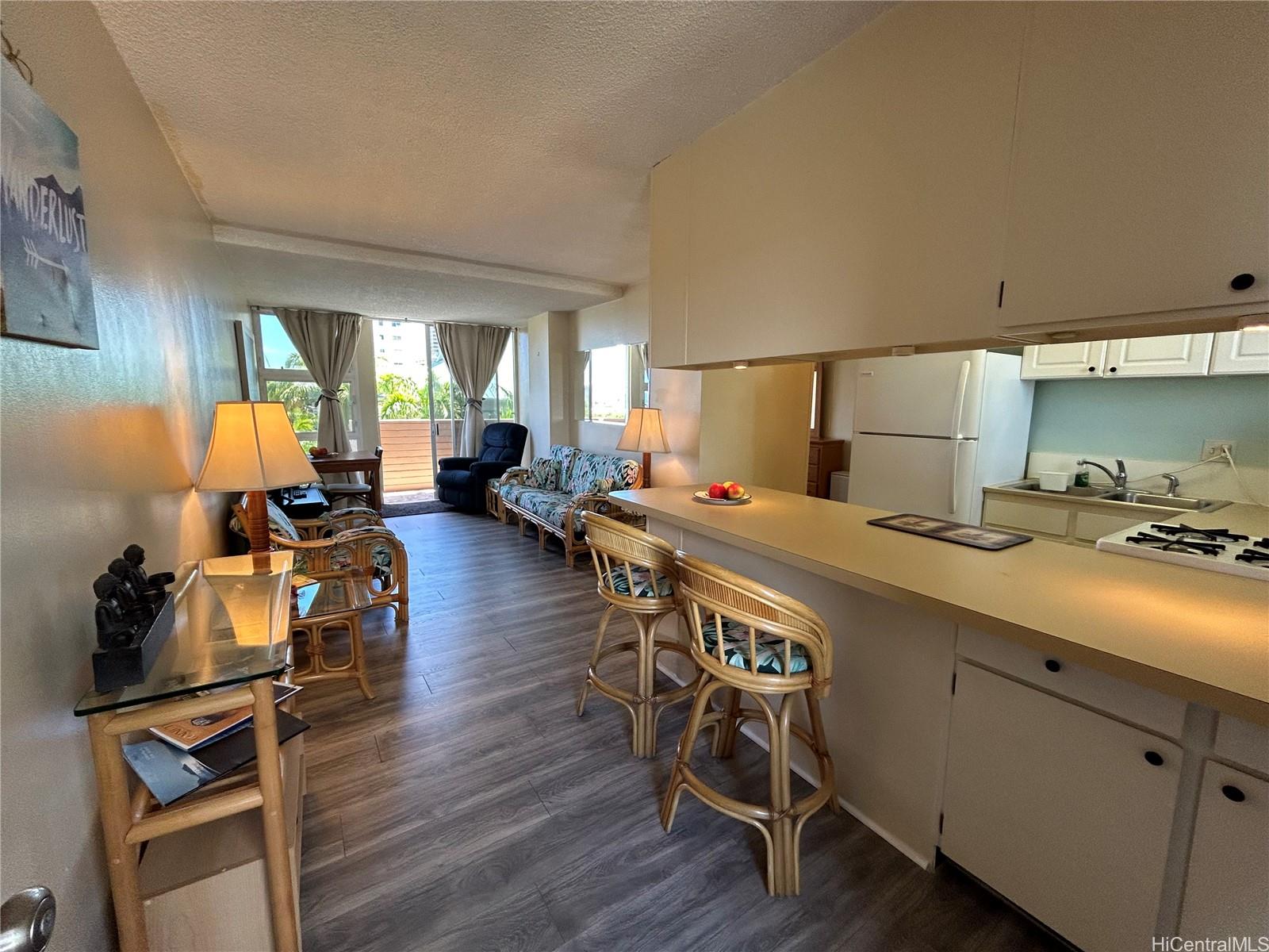 454 Nāmāhana Street, Unit 701 Honolulu, HI 96815 - Photo 4 of 25 a kitchen with a table chairs refrigerator and wooden floor
