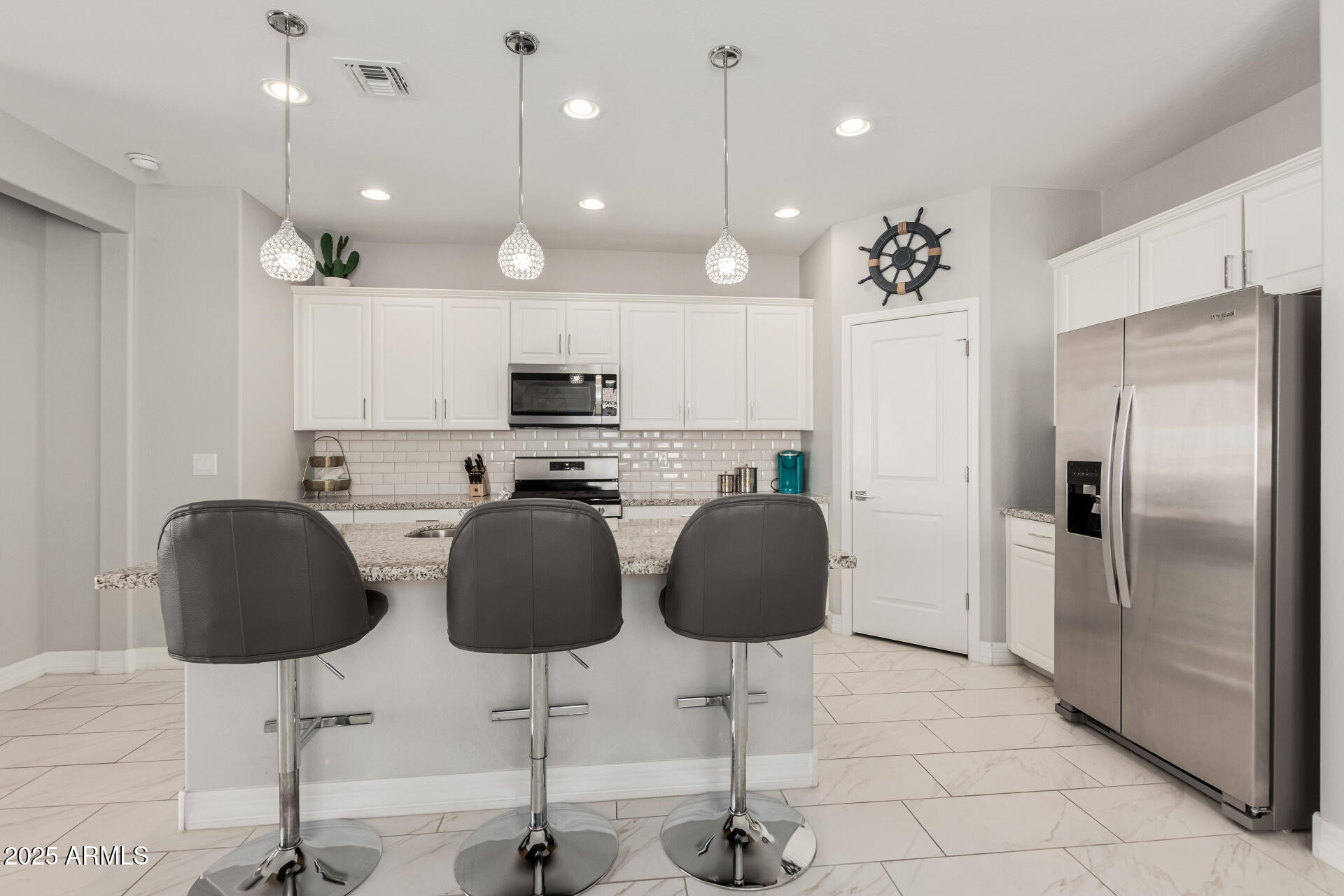 17784 West Sandy Road Goodyear, AZ 85338 - Photo 17 of 38 a kitchen with stainless steel appliances kitchen island granite countertop a refrigerator and chairs