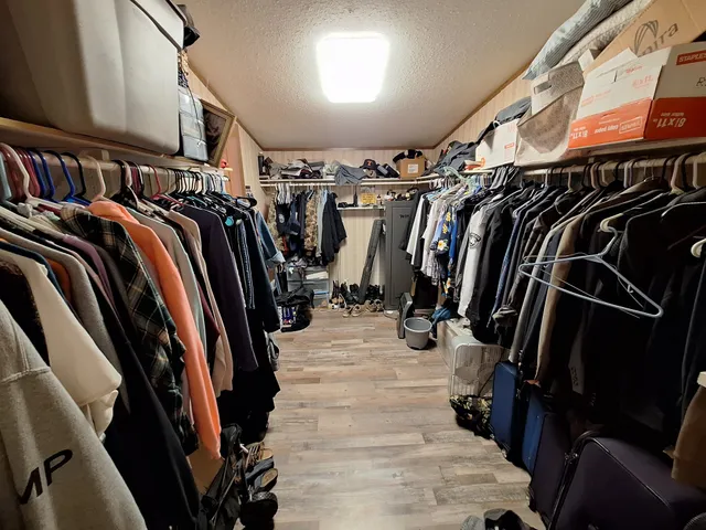 a view of walk in closet with clothes and shoes