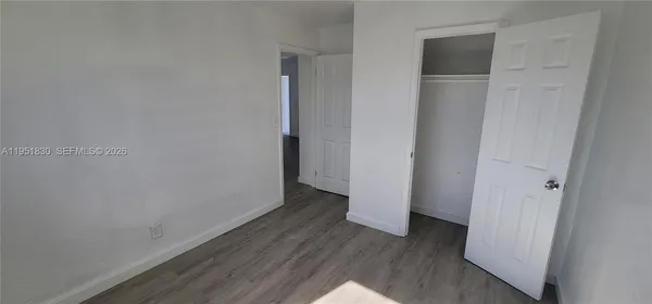a view of an empty room with wooden floor and closet