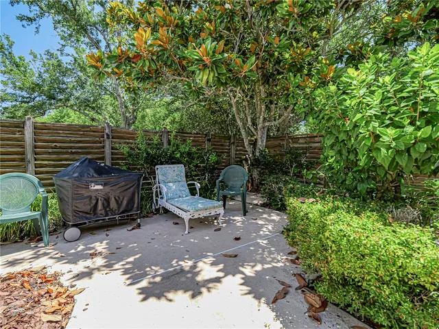 a view of a patio with table and chairs potted plants and large tree