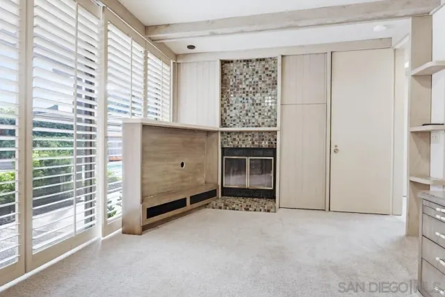 a view of an empty room with a fireplace and a window