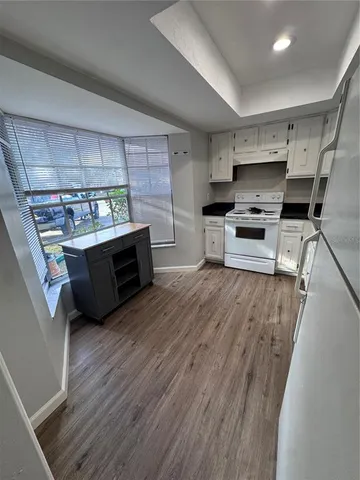 a kitchen with stainless steel appliances a stove a sink a refrigerator wooden floor and cabinets