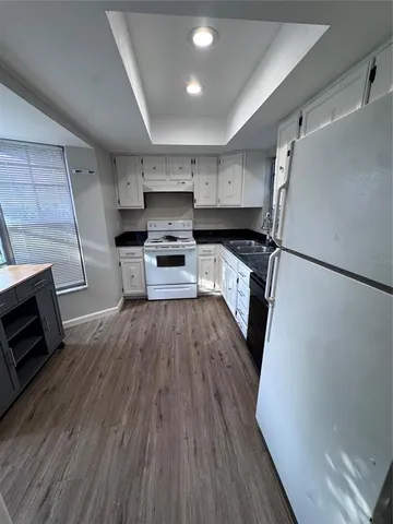 a kitchen with a refrigerator a stove top oven a sink and wooden floor