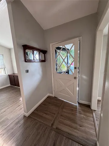 a view of a hallway to room with wooden floor and ceiling fan