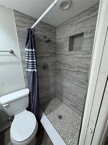 a white toilet sitting next to a shower