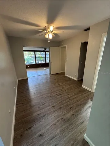an empty room with wooden floor chandelier fan and windows