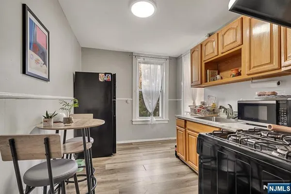 a kitchen with stainless steel appliances granite countertop a stove a refrigerator a kitchen island a dining table and chairs with wooden floor