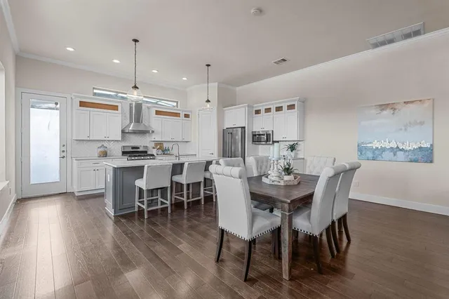 a kitchen with stainless steel appliances kitchen island granite countertop a dining table chairs and sink