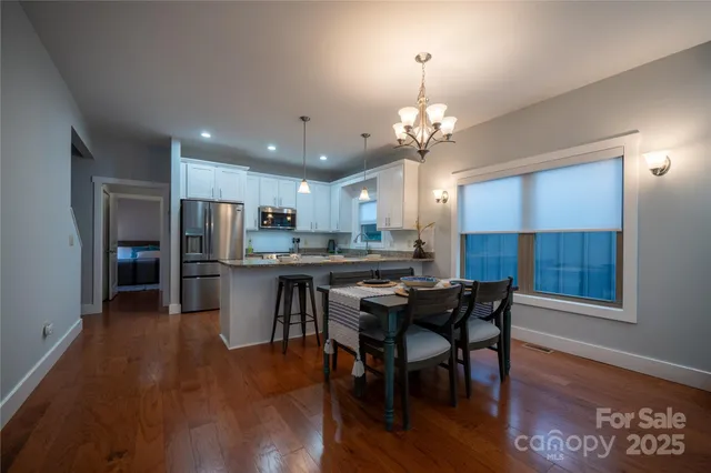 a kitchen with stainless steel appliances kitchen island granite countertop a table chairs refrigerator and microwave