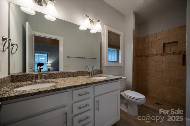 a bathroom with a granite countertop sink a toilet and a mirror