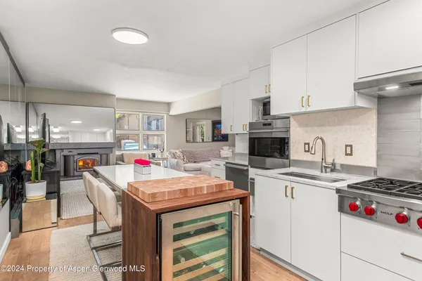 a kitchen with a stove a sink dishwasher and a refrigerator with wooden floor