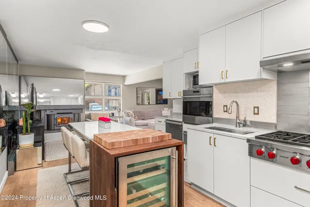 a kitchen with a stove a sink dishwasher and a refrigerator with wooden floor
