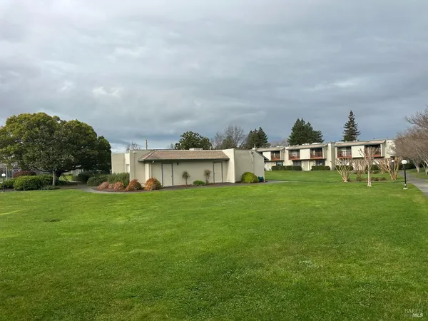 a view of a house with a big yard and large trees