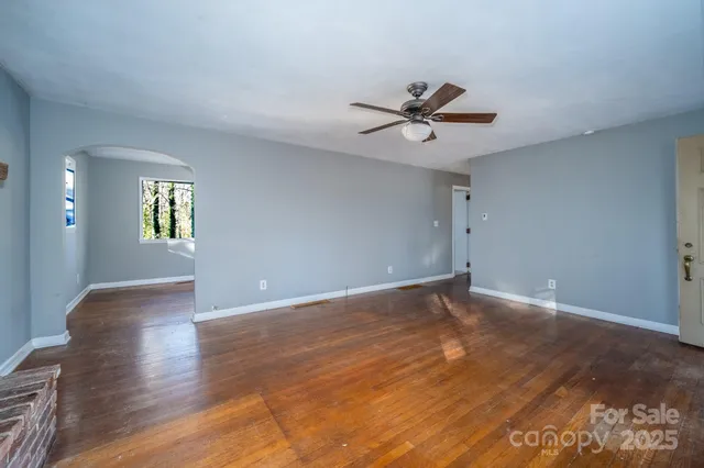 a view of an empty room with window and wooden floor