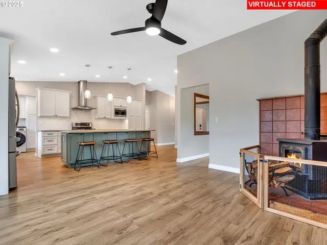 a kitchen with kitchen island stainless steel appliances a dining table chairs and a wooden floor