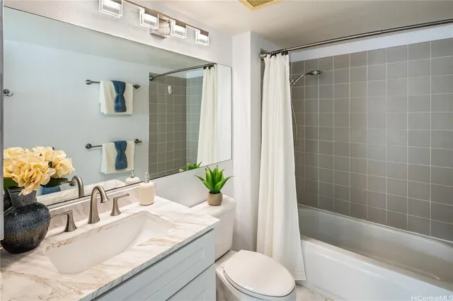 a bathroom with a granite countertop bathtub sink vanity mirror and toilet