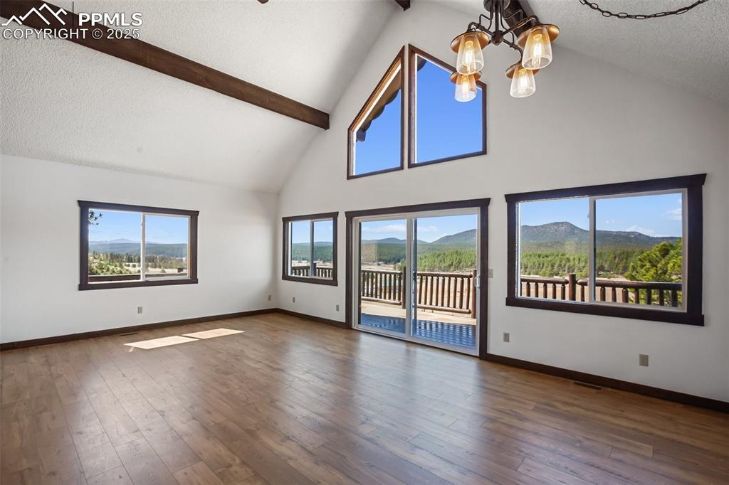 39609 Highway 24 Lake George, CO 80827 - Photo 11 of 46 Empty room featuring high vaulted ceiling, baseboards, beamed ceiling, and a chandelier