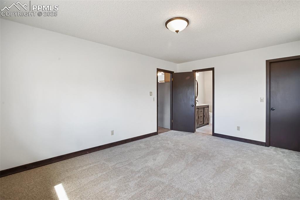 39609 Highway 24 Lake George, CO 80827 - Photo 14 of 46 Unfurnished bedroom with a textured ceiling, baseboards, light carpet, and ensuite bathroom