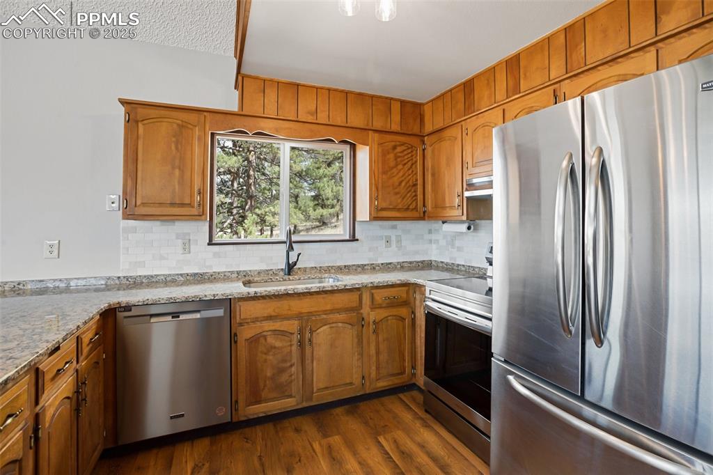 39609 Highway 24 Lake George, CO 80827 - Photo 5 of 46 Kitchen with appliances with stainless steel finishes, brown cabinetry, a sink, and tasteful backsplash