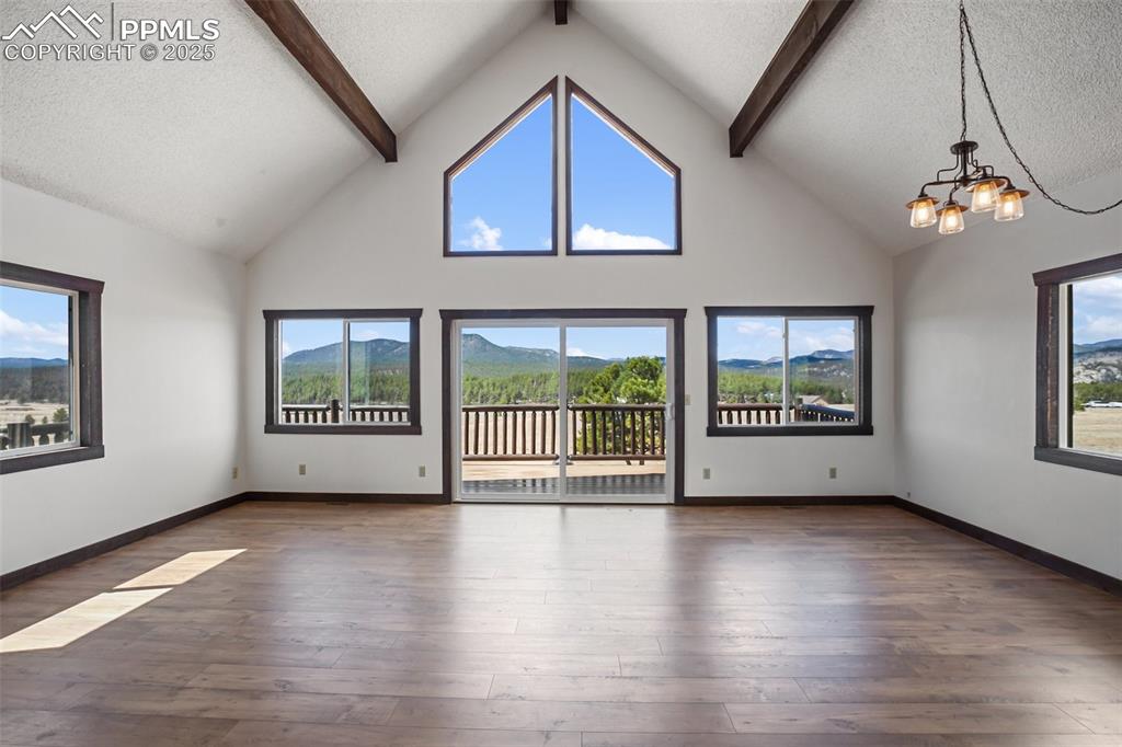 39609 Highway 24 Lake George, CO 80827 - Photo 10 of 46 Unfurnished living room with a textured ceiling, beam ceiling, high vaulted ceiling, an inviting chandelier, and hardwood / wood-style floors
