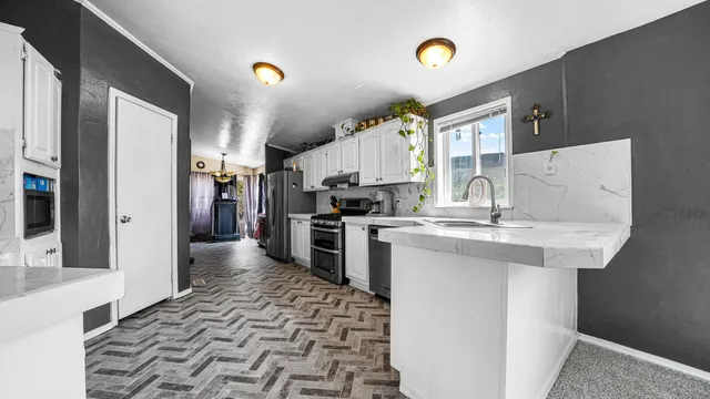 a kitchen with granite countertop a sink cabinets and stainless steel appliances