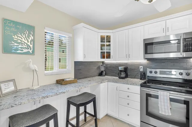 a kitchen with granite countertop a sink cabinets stainless steel appliances and a window