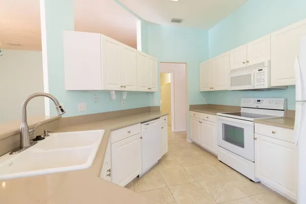 a kitchen with granite countertop white cabinets and white appliances